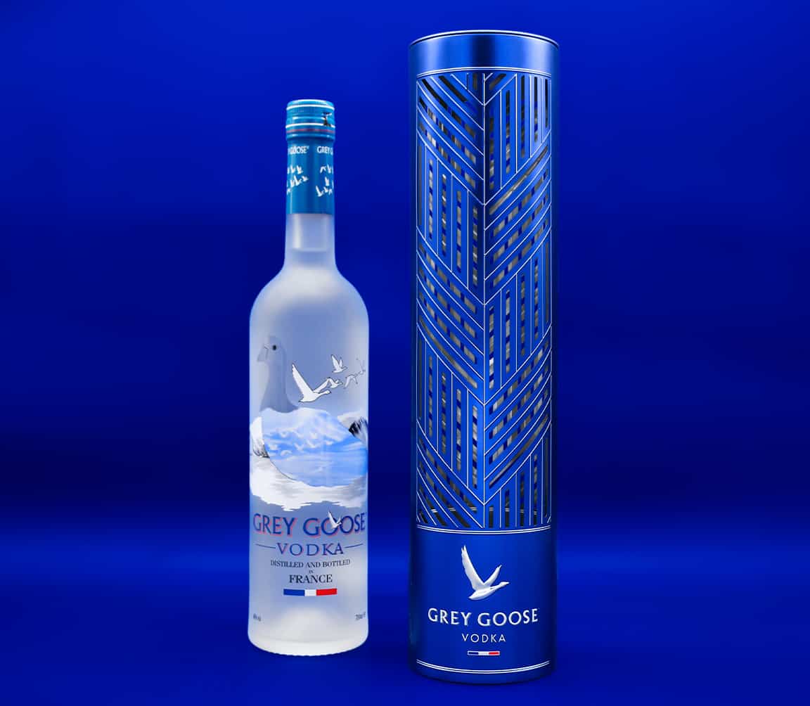 Photo du coffret avec la bouteille Grey Goose à coté. Le tout sur un fond bleu